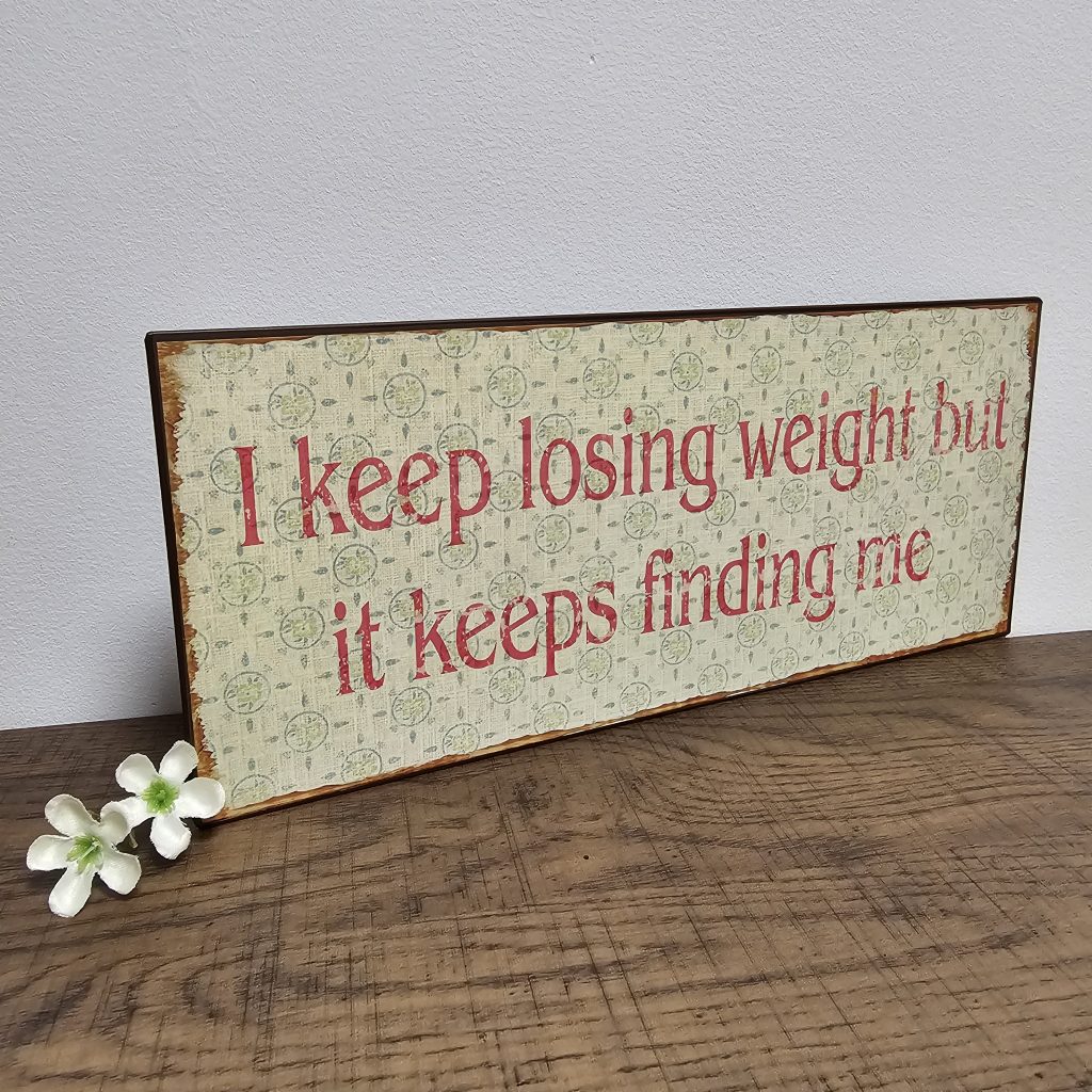 oblong shape tin metal sentiment sign shabby chic pattern neutral colour with distressed finish I Keep Losing Weight But It Keeps Finding Me